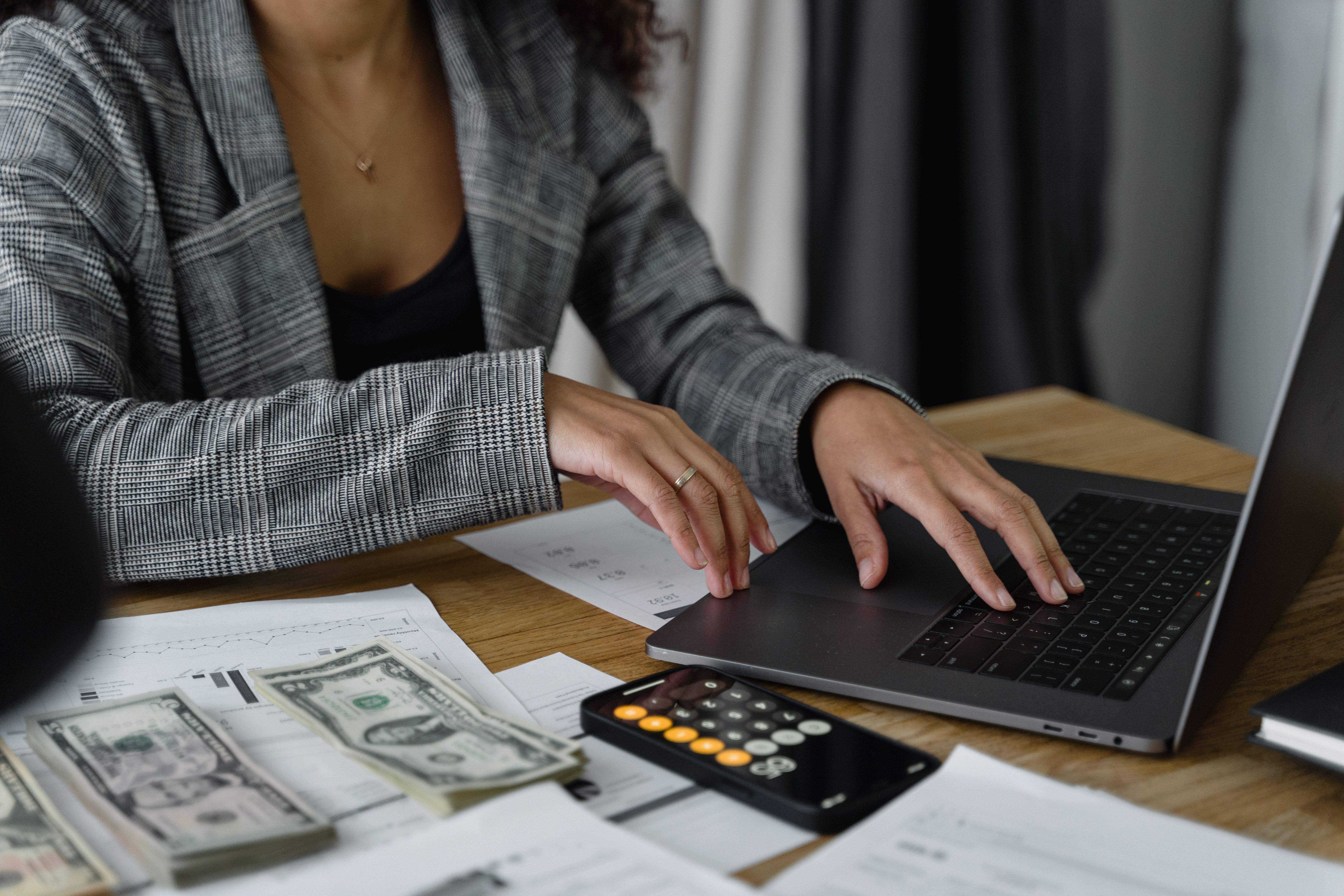 Woman with hands on laptop and bills