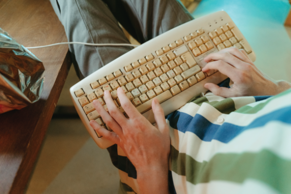 Person types on an old keyboard in their lap