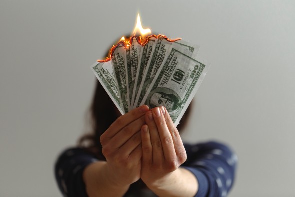 Hands holding six hundred dollar bills on fire