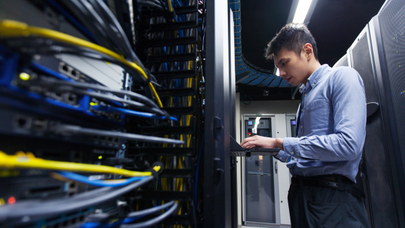 Man working at laptop among servers and wires