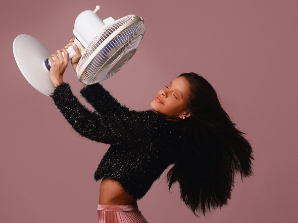 Girl holding fan on light purple background