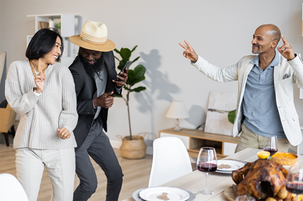 Three people dancing next to a table with a holiday meal