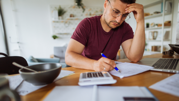 Man paying bills at kitchen table, stressed