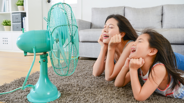 Mom and daughter staying cool in front of blue fan