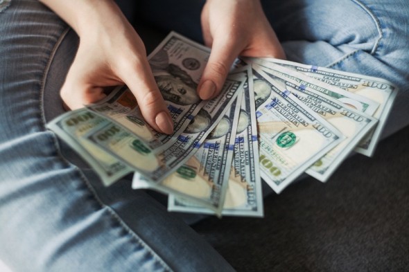 Hands holding one hundred dollar bills