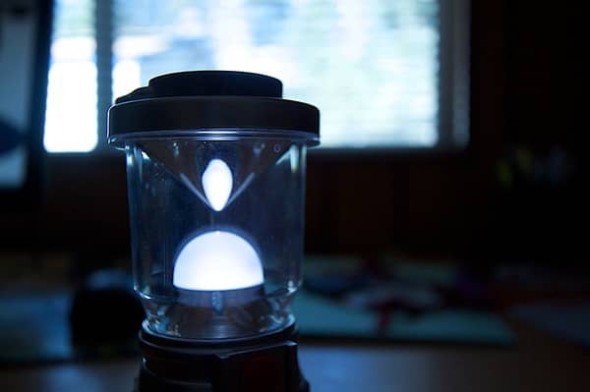 A battery powered lantern sits indoors on a table during a power outage