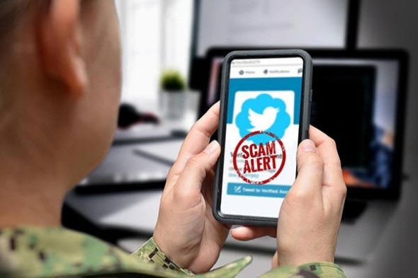 Person holding cell phone with a scam alert message on the screen