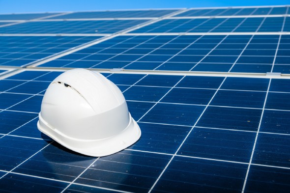 Solar array with a white hard hat, blue sky in the background