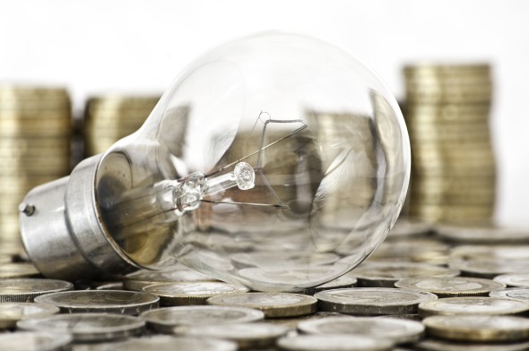 Light Bulb resting on coins with white background