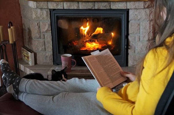 Woman reading by a gas fireplace