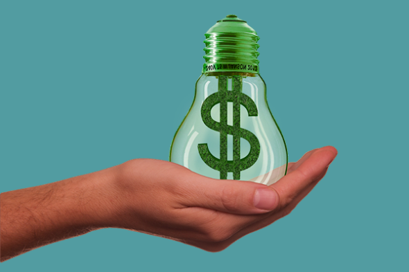 Hand holding a green light bulb with a dollar sign in it on a blue background