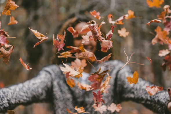 Woman in gray throwing red leaves on a dark background