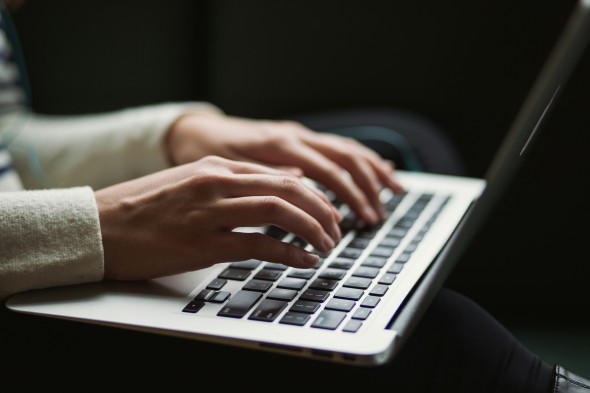 White hands on a laptop, dark background