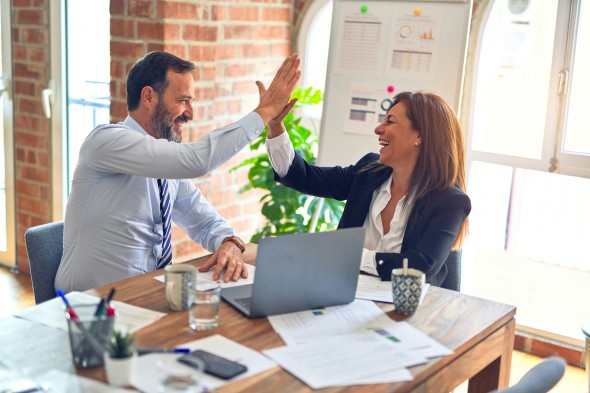 Two people high-fiving in office environment 