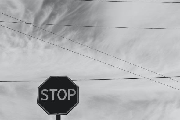 Black and white image of a stop sign with power lines in the background