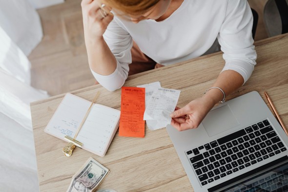 Woman looks at bills with a hand to her head
