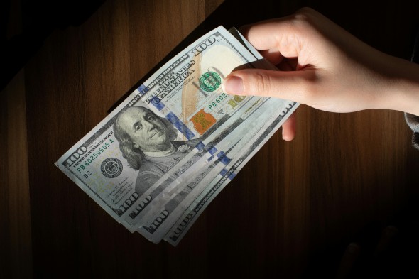 Multiple 100 dollar bills on a dark background