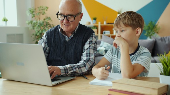 Senior and kid looking at laptop doing homework