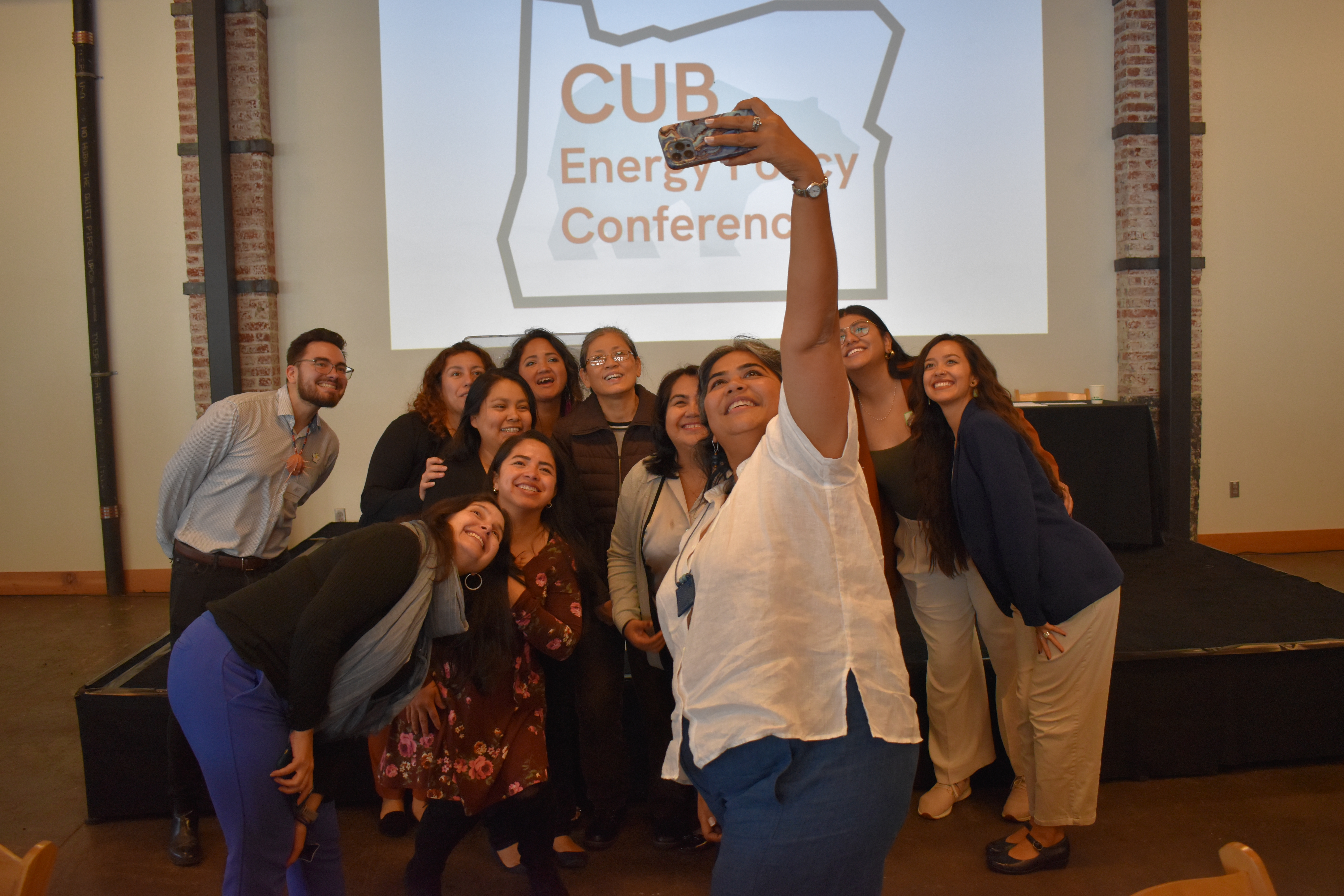 A group takes a selfie in front of the CUB conference logo